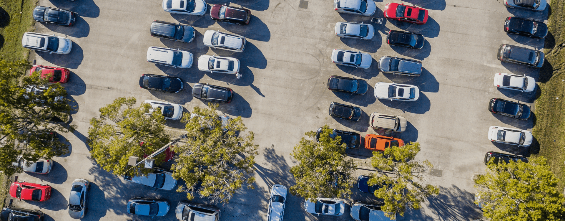 Fotografia de um parque de estacionamento com vários de carros visto de cima